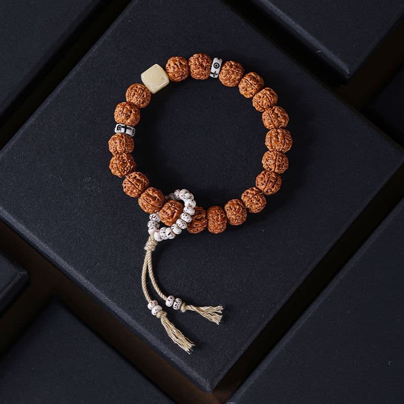 Rudraksha Bodhi bracelet with silver spacers, bone accent bead and tassel on dark surface
