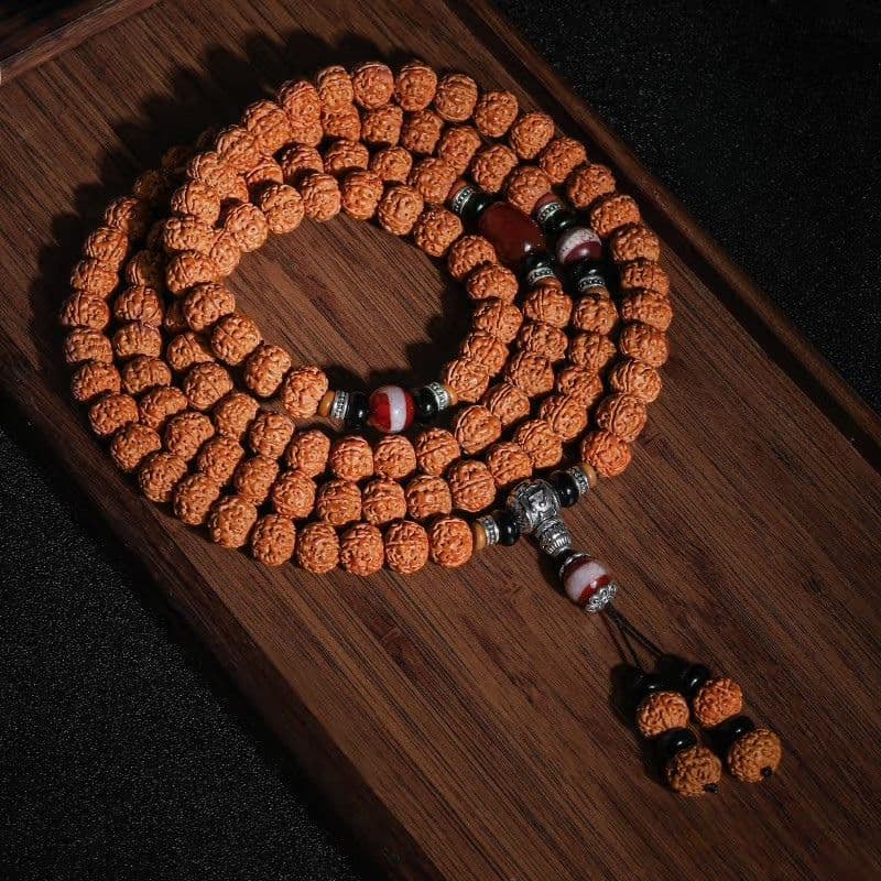 108-Bead Rudraksha Mala with an accent bead and carved pendant on dark wood