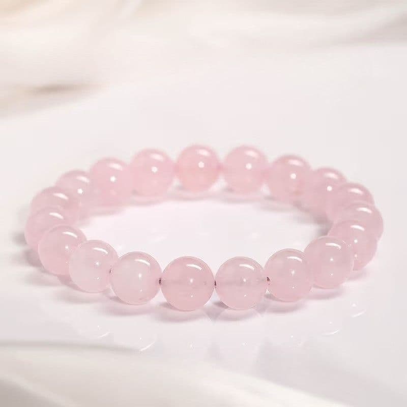 Rose quartz wrist mala bracelet with 22 polished 10mm beads on dark wood