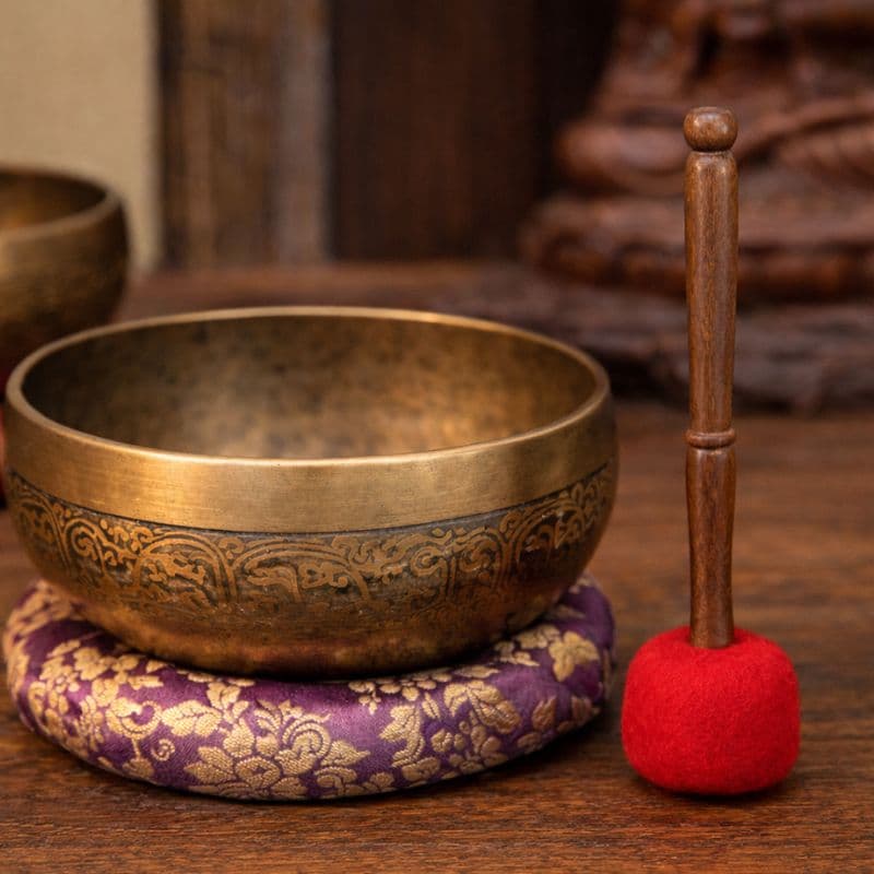 Wool Singing Bowl Mallet with red wool head and wooden handle, displayed next to a brass singing bowl on a silk cushion